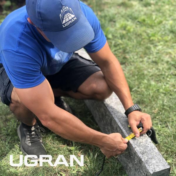 A UGRAN surveyor checking a kerb with a tape measure on site